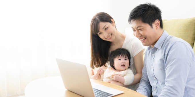 ライフプランニング内容をPC画面で確認する夫婦と赤ちゃん